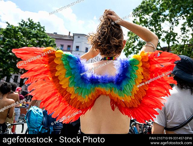 10 July 2021, Berlin: A participant of a bicycle demonstration under the motto ""No Nipple is free until all Nipples are free!"" wears rainbow-colored wings