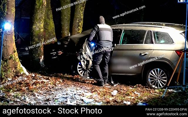 07 December 2023, Lower Saxony, Ganderkesee: A police officer stands next to a vehicle involved in an accident. A driver crashed his vehicle into a tree in...