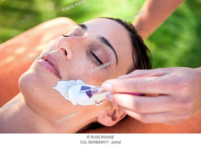 Woman in spa environment, face mask being applied to her face