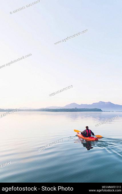 Woman standing on sup board in the morning on a lake, Germany