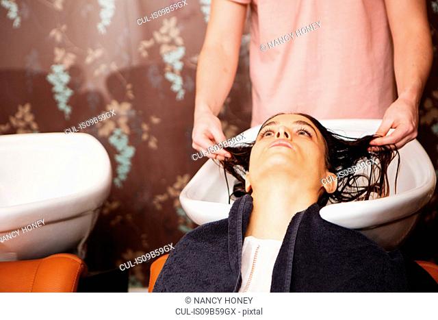 Female customer having hair washed in salon sink