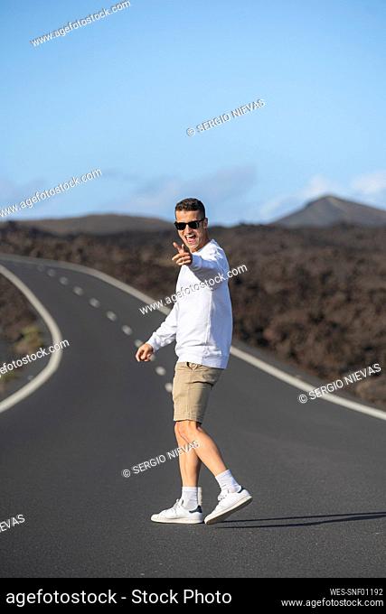 Happy male tourist gesturing while standing on road
