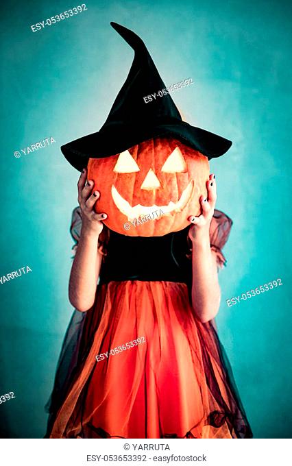 Funny child dressed witch costume. Kid painted terrible pumpkin. Halloween autumn holiday concept