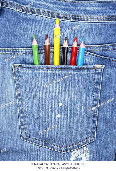 wooden colored pencils in the back pocket of blue jeans, close up, full frame