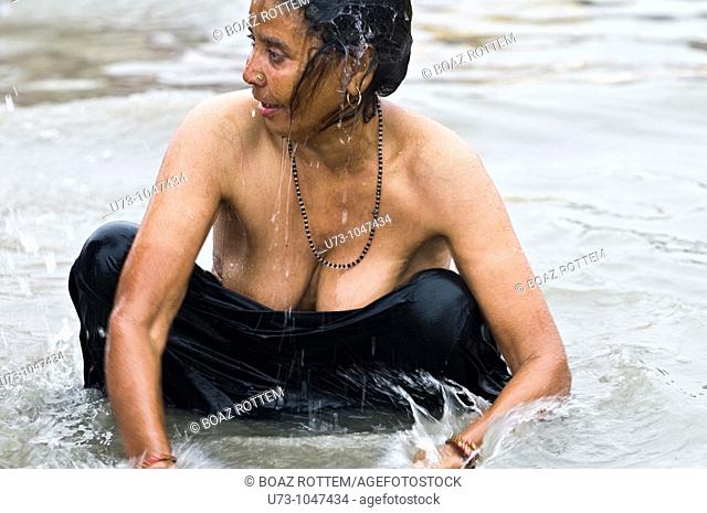 An Indian woman bathing in the holy water of Gangasagar island during the annual Gangasagar mela