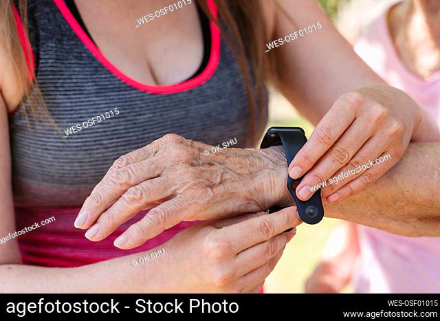 Fitness instructor adjusting smart watch on senior woman's hand