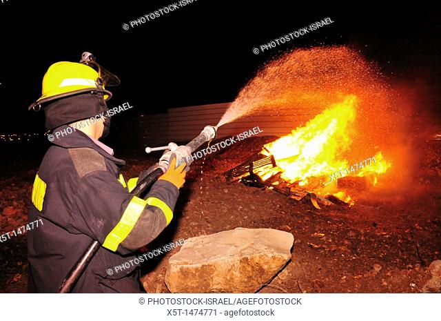 Israel, Haifa, Firefighter stands next to a large bonfire during the lag b'omer celebrations Lag B'Omer is a day for bonfire celebrations