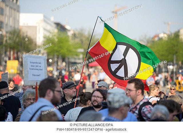 18 April 2018, Germany, Berlin: Protestors wave a peace flag at the rally 'Nein zum Krieg' (lit. no to war) of The Left party