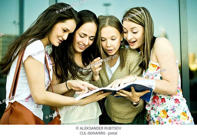 Four young female friends looking and laughing at notebook