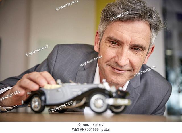 Mature man playing with classic car model