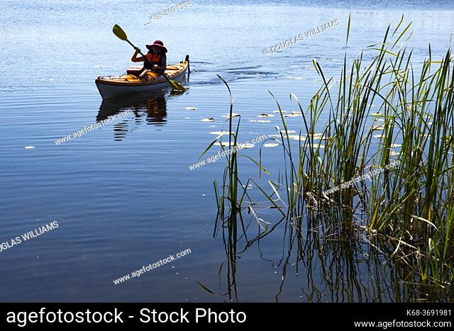 Woman, 70, paddles a kayak on Watch Lake, British Columbia, Canada