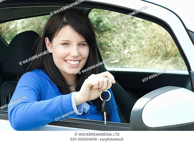 Happy teen girl sitting in her car holding keys after bying a new car