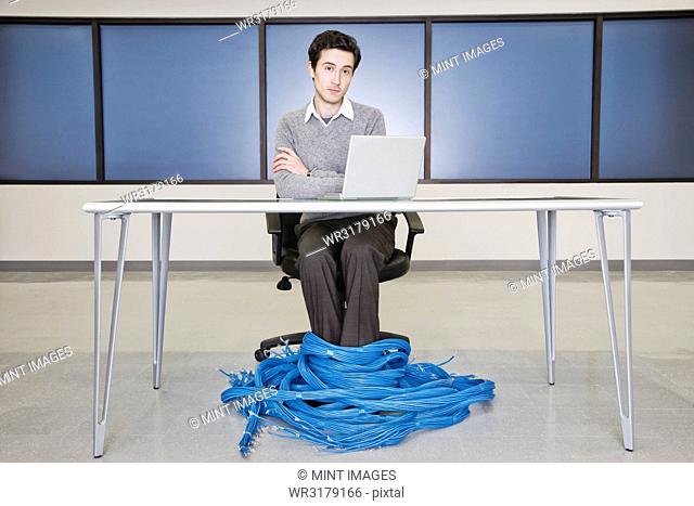 Caucasian businessman wrapped up in CAT 5 computer cables from a computer server farm