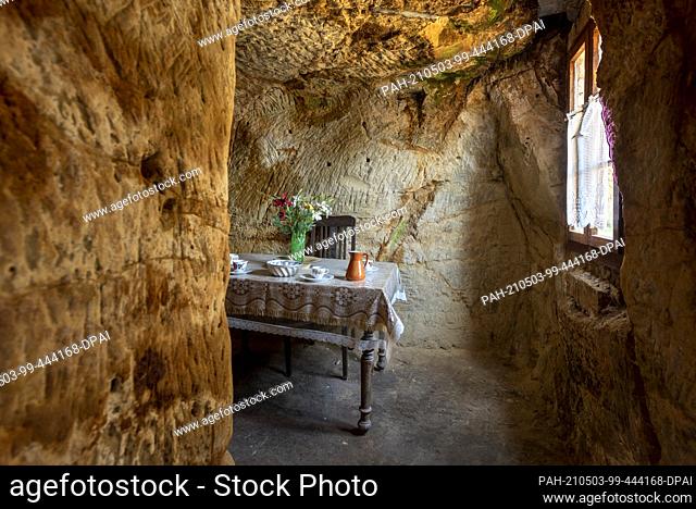 28 April 2021, Saxony-Anhalt, Halberstadt: A laid table stands in a cave dwelling on the Schäferberg. The cave dwelling of Langenstein is reminiscent of the...