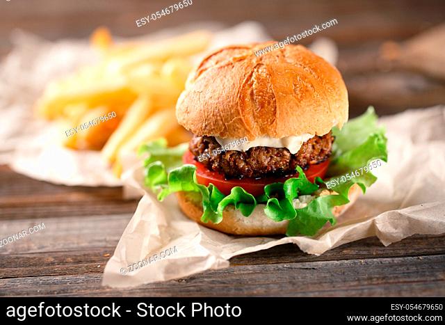 Homemade burger with french fries on wooden table