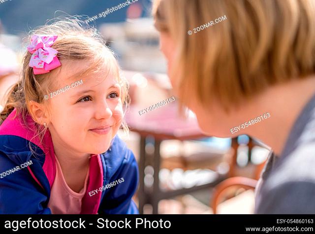 Daughter and mother sitting in a restaurant and talking, summer day on holidays