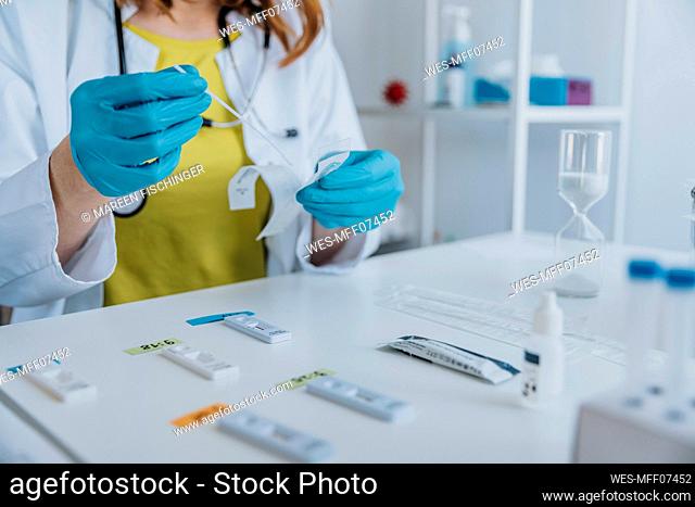 Doctor removing nasal swab sample while testing at examination room