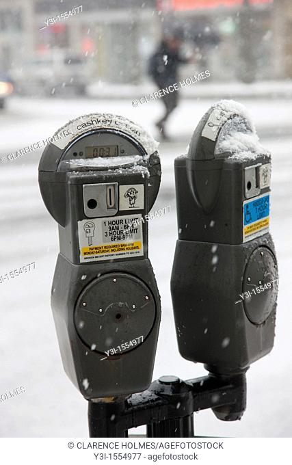 Coin operated parking meters in a snowstorm in White Plains, New York, USA