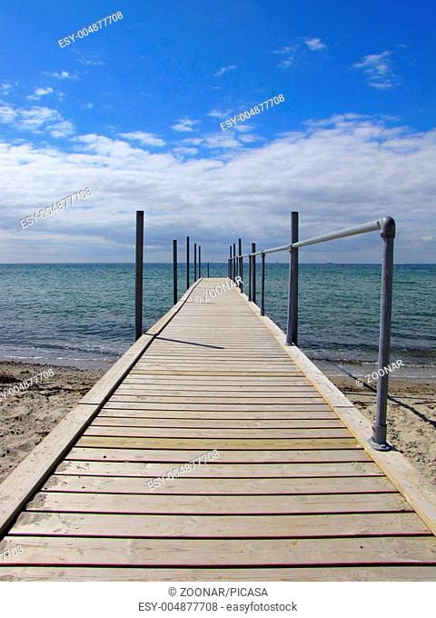 A wooden jetty goes into the beautiful blue sea