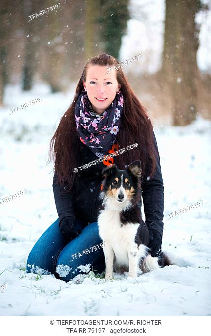 woman sits with sheltie in snow