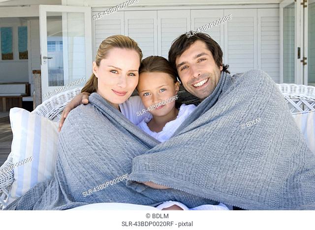 Family relaxing on sofa under blanket