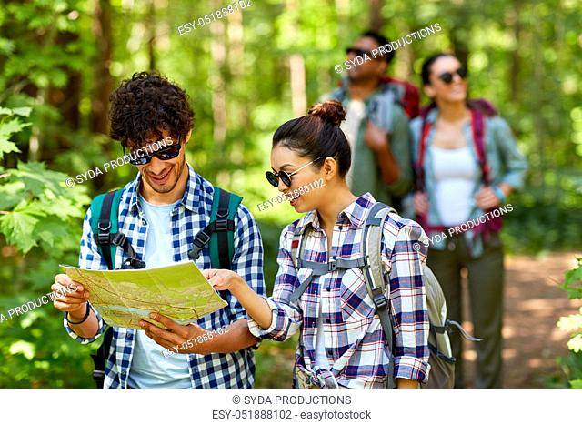 friends with map and backpacks hiking in forest