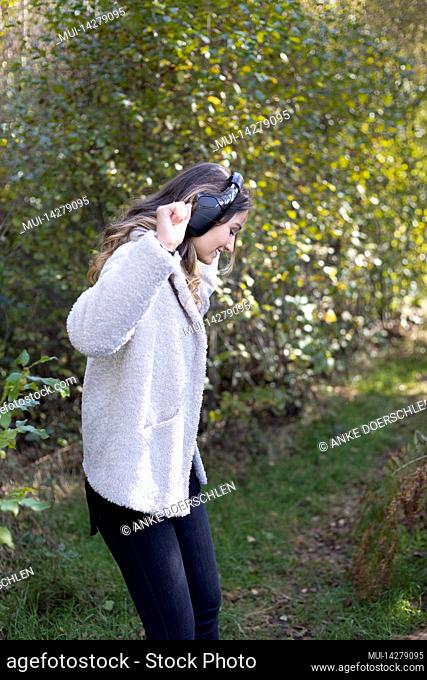 Young woman with headphones dancing to music in forest