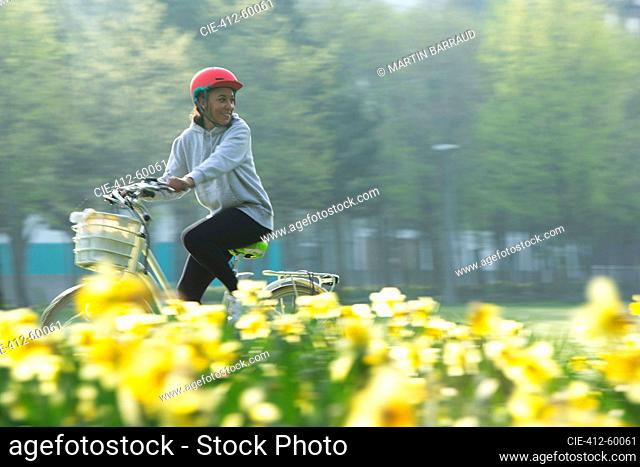 Happy young woman riding bicycle in sunny spring park