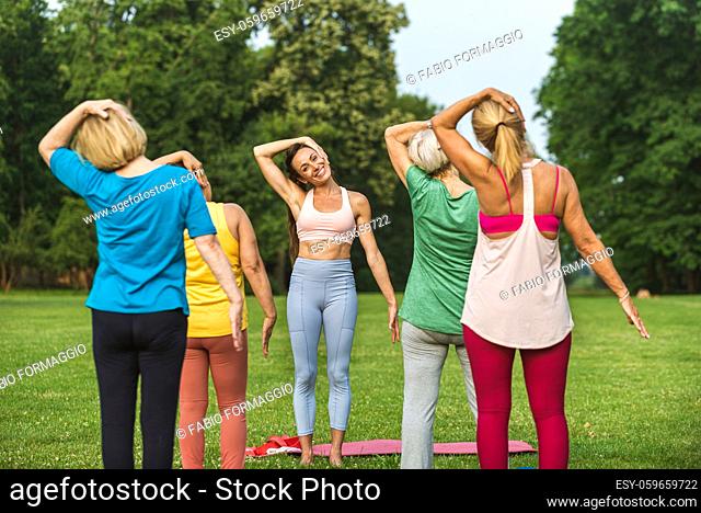 Multiethnic group of senior women training at park with fitness instructor - Active elderly people doing sport in the nature