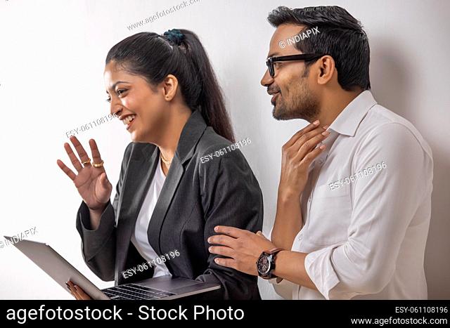 Office colleagues smiling together while doing office work using laptop