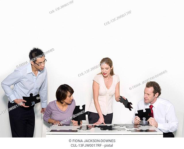 Four business people doing a jigsaw