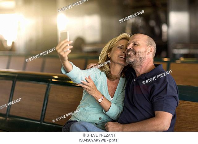 Mature couple photographing themselves on passenger ferry