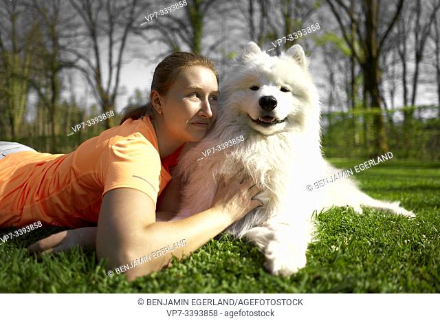 woman laying next to dog on meadow in park, at Herrenchiemsee, Chiemsee, Bavaria, Germany
