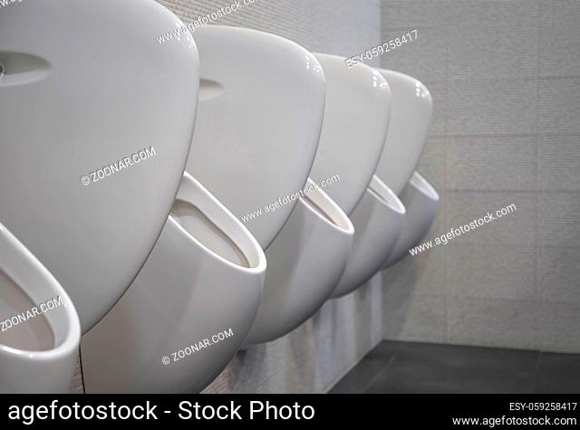 Closeup white urinals in men's bathroom, the design of white ceramic urinals for men in the toilet room. public men toilet room, WC