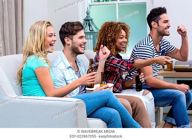 Cheerful multi-ethnic friends enjoying soccer match at home