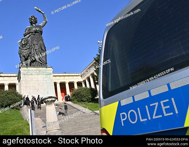 19 September 2020, Bavaria, Munich: A police car is parked on the Wiesn grounds below the Bavaria statue, policemen stand on the stairs in front of the statue