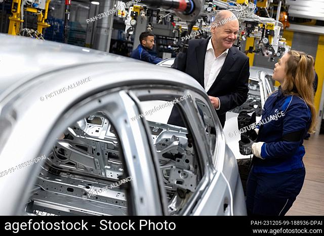05 December 2023, Bavaria, Munich: Federal Chancellor Olaf Scholz (SPD) takes part in a tour of the BMW plant and is shown around production by an employee