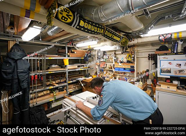 14 September 2023, Schleswig-Holstein, Kiel: On-board carpenter Daniel Pawlinski cuts a wooden strip in the on-board carpentry workshop below deck of the sail...