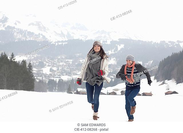 Happy couple running in snowy field