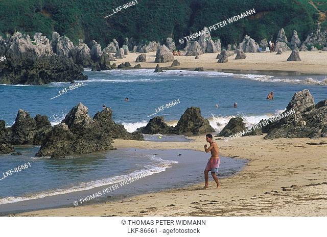 Spiky rocks and bathing people at the sandy beach Playa de Toro, Llanes, Asturias, Costa Verde, Bay of Biscay, Northern Spain