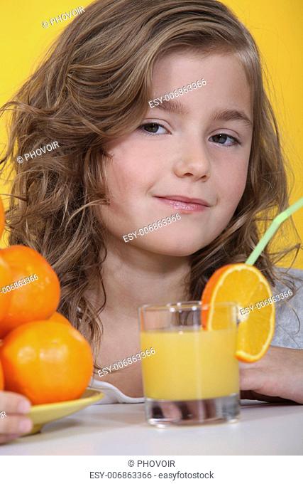 Portrait of an adorable girl drinking a glass of orange juice