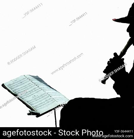 Music busker playing a recorder and following the sheet music on a music stand