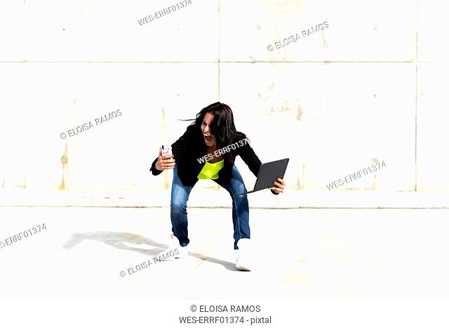 Woman holding smartphone and tablet, screaming and taking a selfie