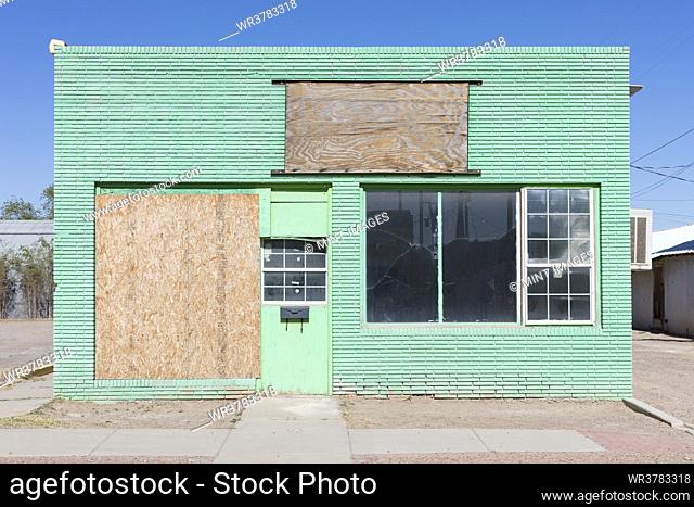 Abandoned roadside store in a small town, boarded up window, green painted exterior