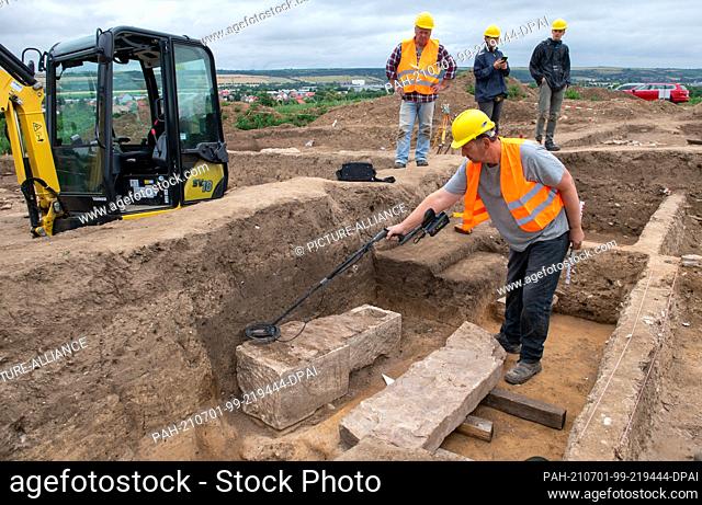 01 July 2021, Saxony-Anhalt, Eisleben: Project manager and archaeologist Felix Biermann examines a sarcophagus on the site of the former royal palace of Helfta...