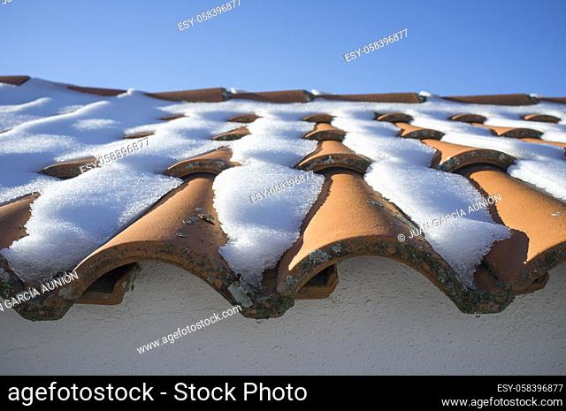 Mediterranean roof tiles covered with snow and ice. Non proper material for snowfalls