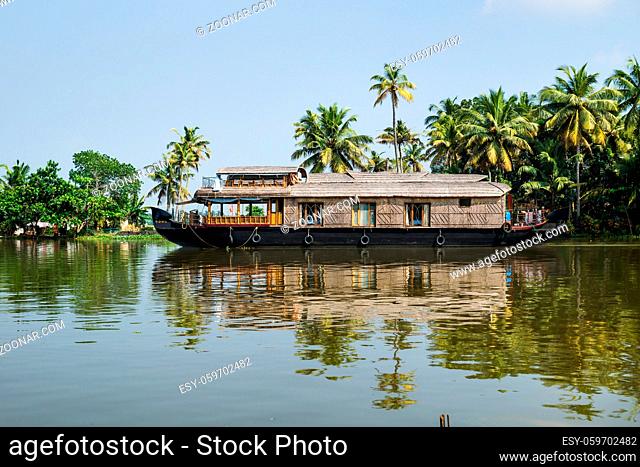 Traditional houseboat in the Kerala backwaters along palm tree coastline at a cloudless sunny day, Alappuzha, Alleppey, India