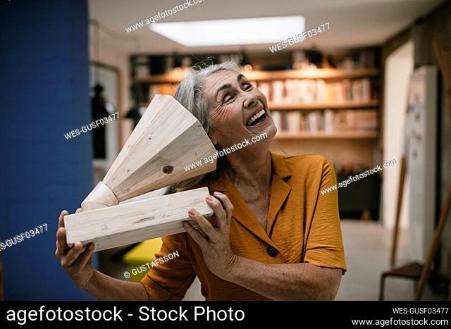Happy grey-haired woman holding wooden grammophone