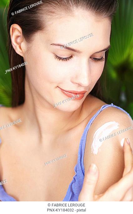 Young woman applying sun cream