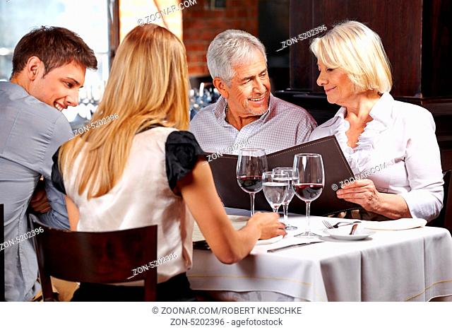 Familie mit zwei Senioren im Restaurant schauen auf die Speisekarte